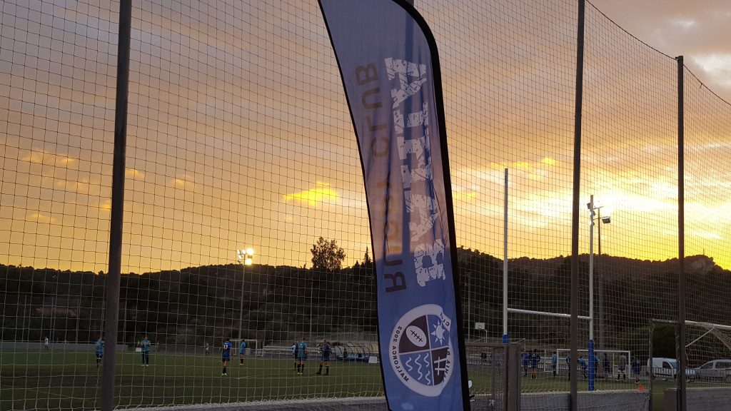 Campo del club al atardecer con la bandera del Bahía Rugby Club